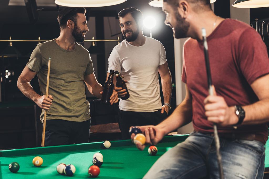 young caucasian men drinking beer beside billiard table in bar  - Photo, Image