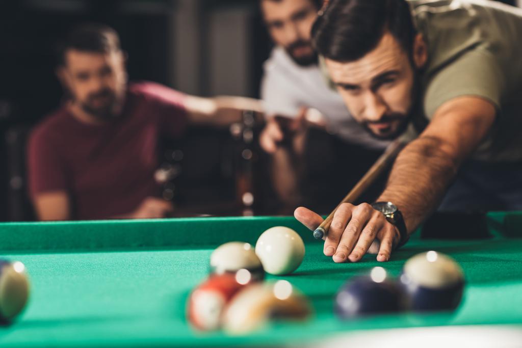 young handsome man playing in pool with friends at bar - Photo, Image