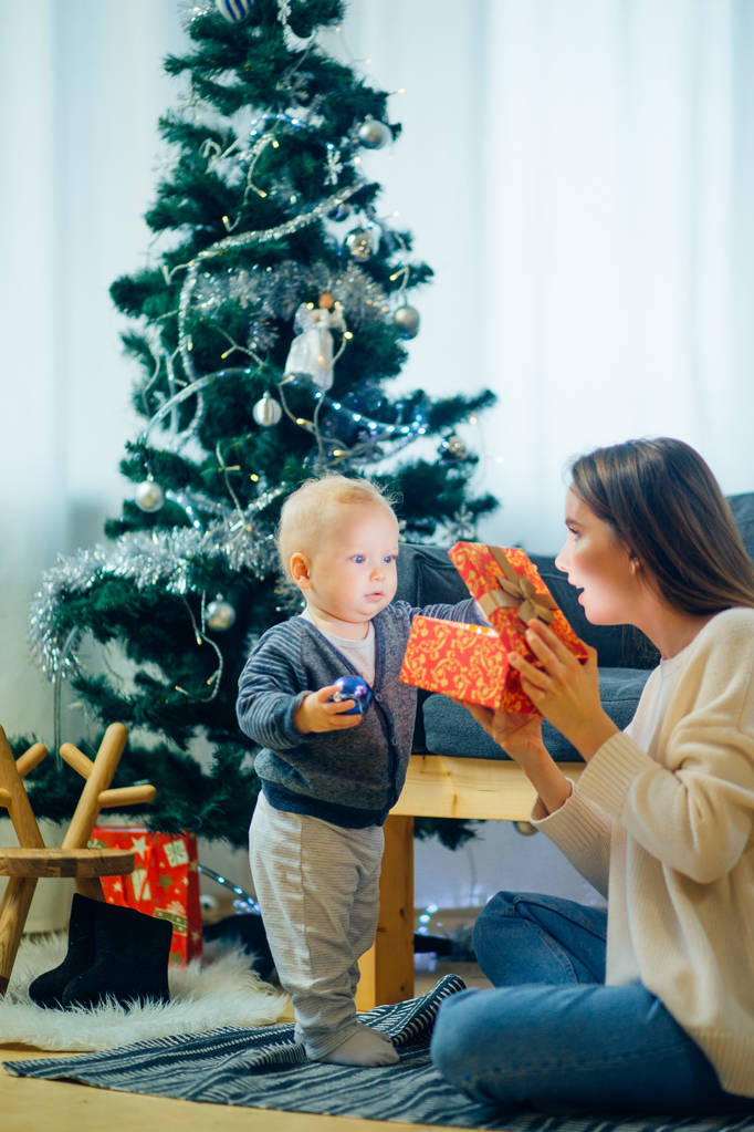 Мать и сын открывают волшебный рождественский подарок на елку в гостиной
 - Фото, изображение
