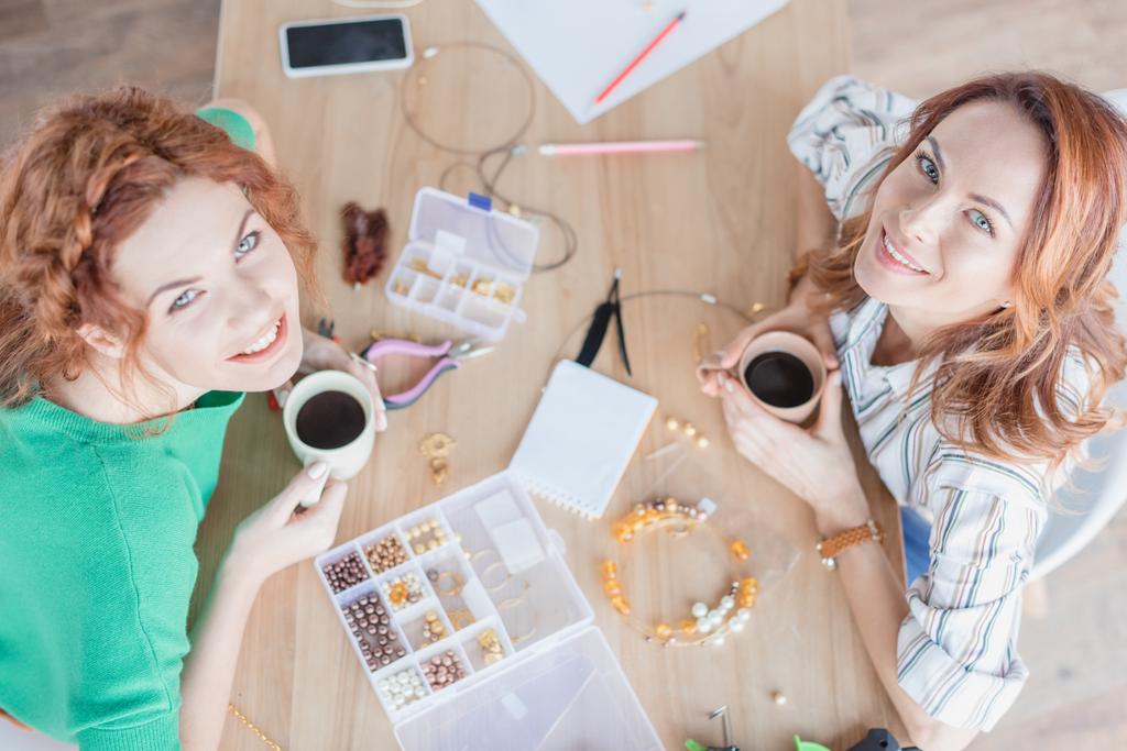 vista ad alto angolo di giovani donne che bevono caffè in officina accessori fatti a mano
 - Foto, immagini