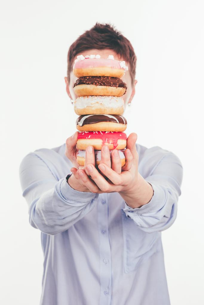 vrouw met stapel donuts voor gezicht geïsoleerd op wit - Foto, afbeelding