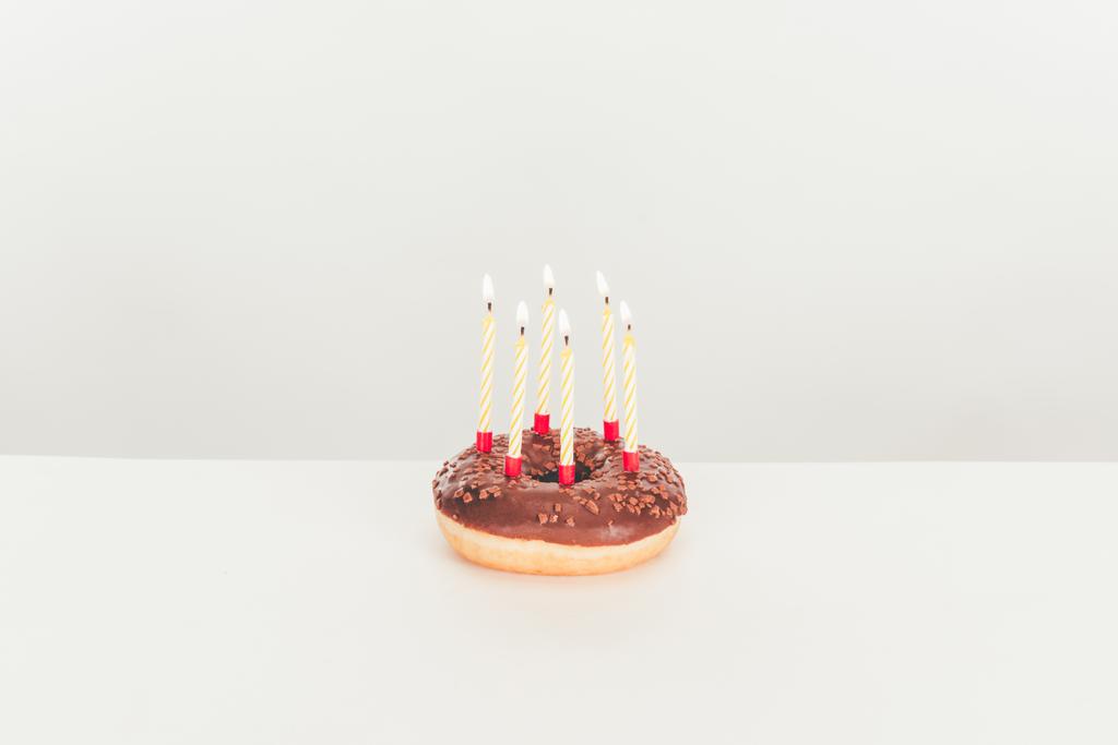 herkullinen lasitettu donitsi syntymäpäiväkynttilöillä valkoisella pöydällä
 - Valokuva, kuva