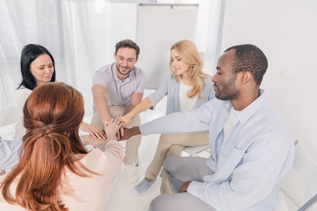 smiling middle aged multiethnic people stacking hands during group therapy - Photo, Image