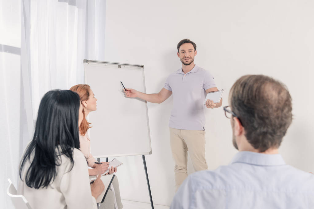 middle aged man pointing at blank whiteboard during anonymous group therapy - Photo, Image
