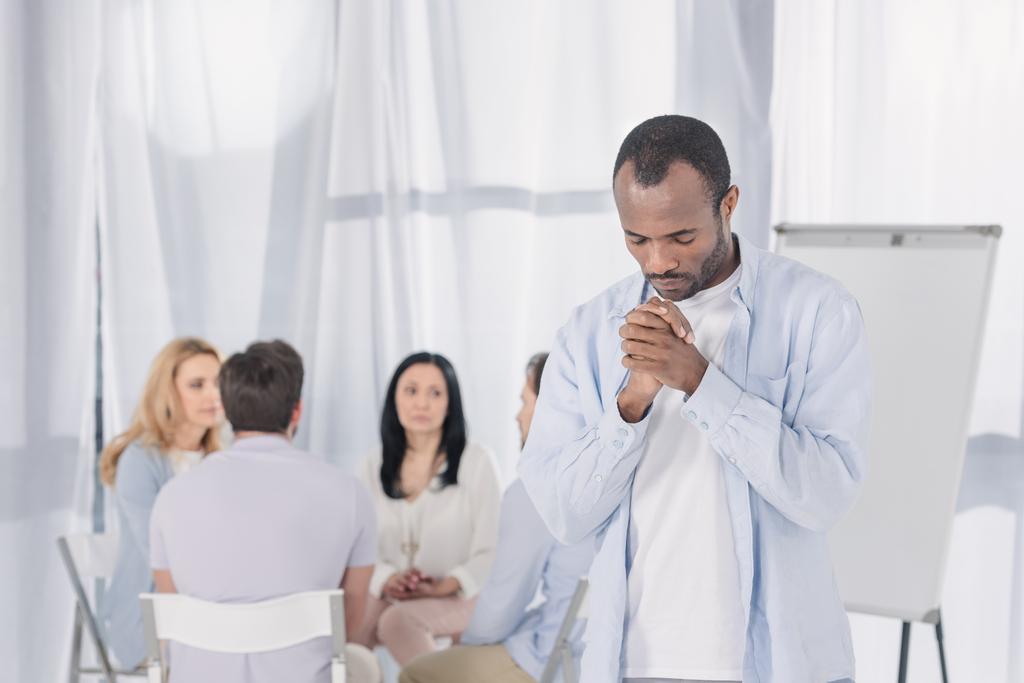 afro-amerikai imádkozó, miközben az emberek mögött ülve, csoport terápia során - Fotó, kép