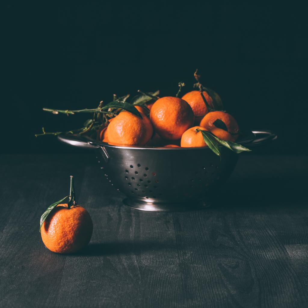 vue rapprochée de la pile de mandarines avec des feuilles dans la passoire sur la table en bois sombre
 - Photo, image