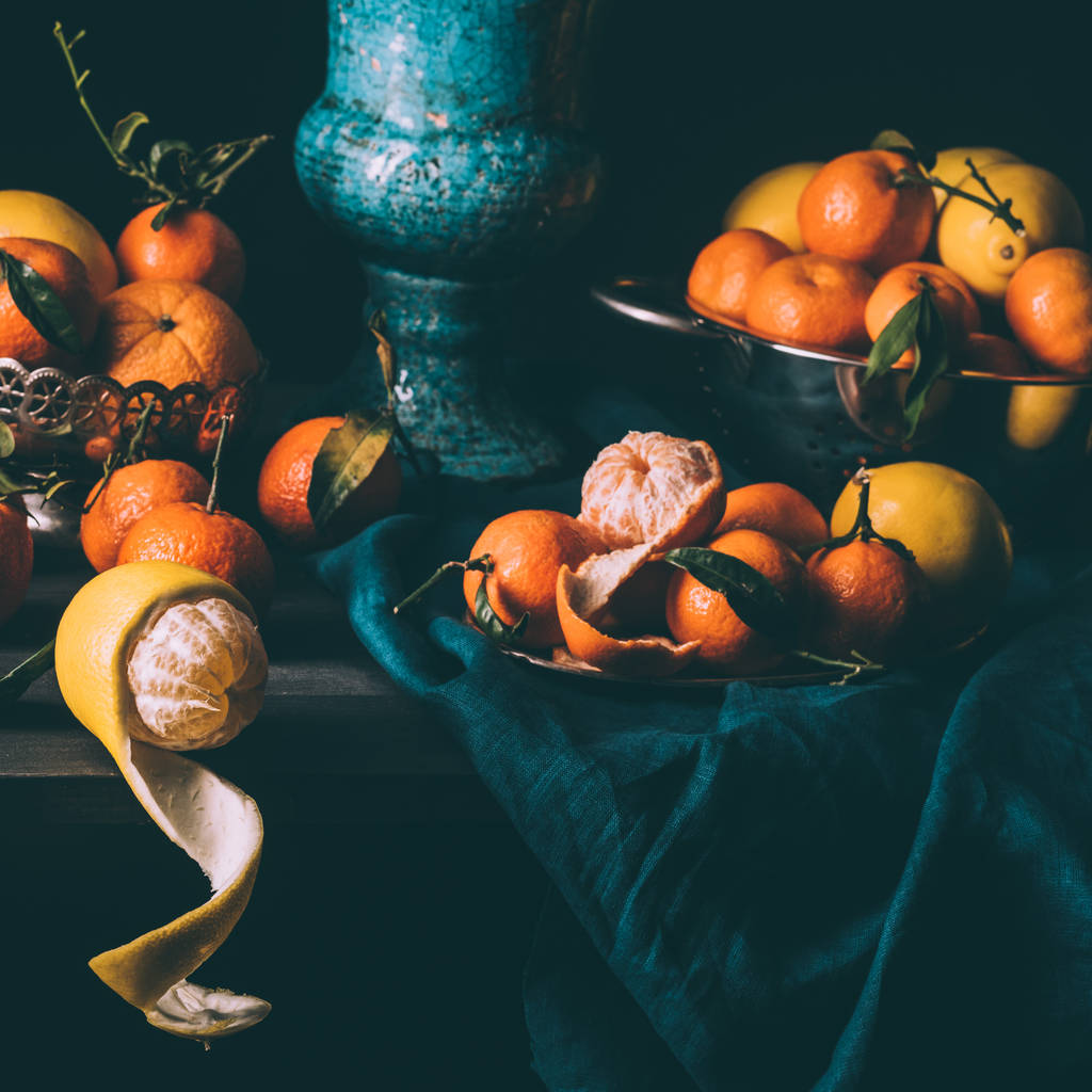 vista de cerca de la disposición de limones frescos y mandarinas en tazón y colador en la mesa con mantel oscuro
 - Foto, Imagen