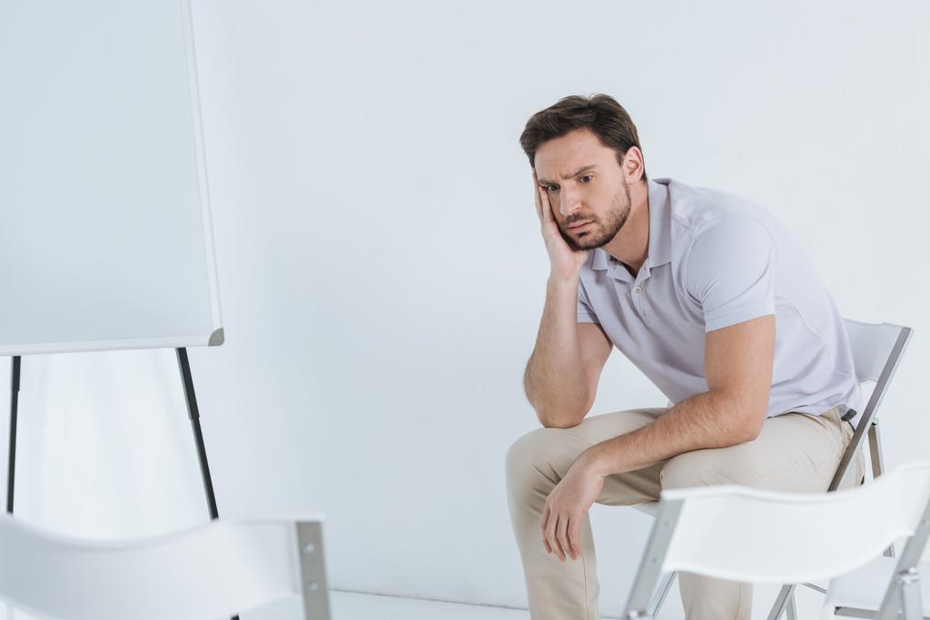 Depressiver Mann sitzt im leeren Raum und schaut weg - Foto, Bild