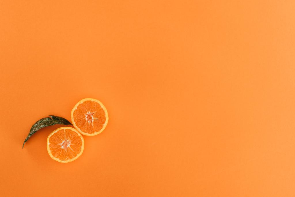 bovenaanzicht van stukken van Oranje en blad geïsoleerd op oranje - Foto, afbeelding