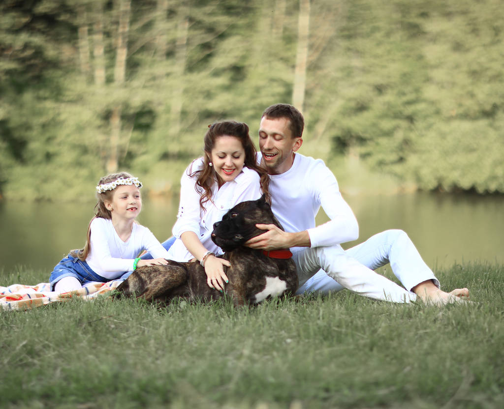 ευτυχισμένη οικογένεια με σκύλο συντροφιάς στο πικνίκ σε μια ηλιόλουστη μέρα του καλοκαιριού. pregn - Φωτογραφία, εικόνα