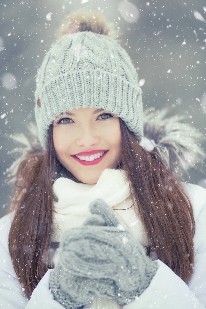 Красивая улыбающаяся молодая женщина в теплой одежде. Концепция портрета в зимнюю снежную погоду
 - Фото, изображение