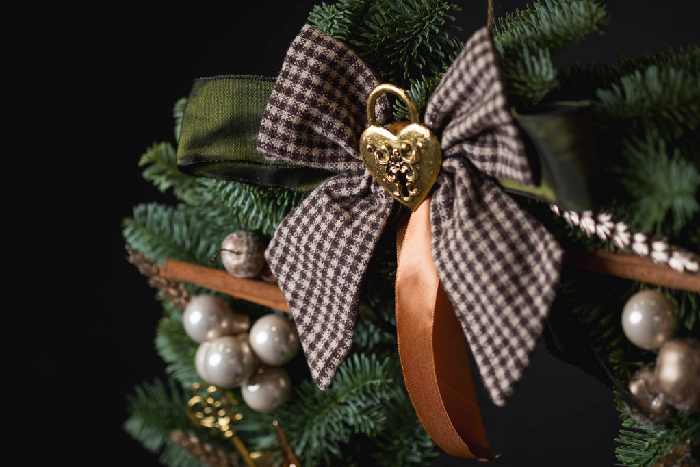 крупным планом Рождественский венок с зелеными ветвями елки, коричневый лук и красивые украшения на черном фоне
 - Фото, изображение