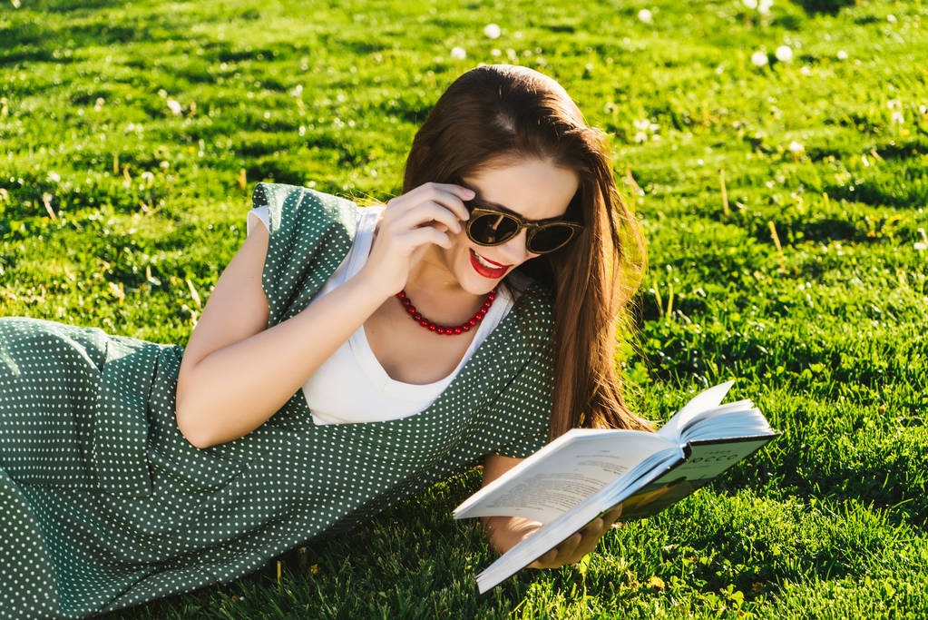 Lectura de la mujer en la hierba. Preparación de los estudiantes en el parque, gafas de sol
 - Foto, Imagen