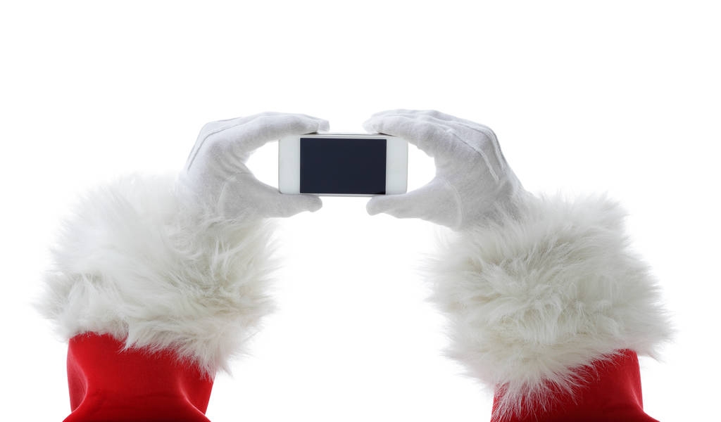 Χριστούγεννα έννοια πυροβόλησε με Santa κρατώντας ένα λευκό έξυπνο τηλέφωνο απομονωμένη σε λευκό - Φωτογραφία, εικόνα