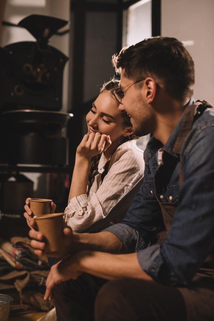 casal sorrindo com xícaras de café tendo pausa durante o trabalho no café
 - Foto, Imagem