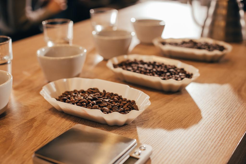 Nahsicht auf arrangierte Schüsseln mit Kaffeebohnen und Kaffeemehl für die Essensfunktion auf Holztischplatte - Foto, Bild