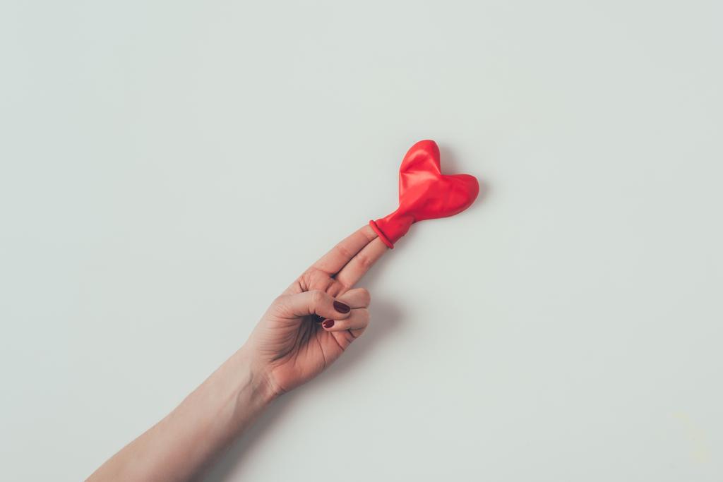 oříznutý obraz balónku ve tvaru srdce na dvou prstech na bílém, valentinovém dni - Fotografie, Obrázek