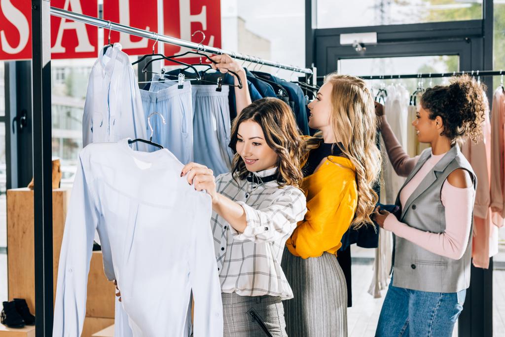groep gelukkige vrouwen op winkelen in kledingsopslag op verkoop dag - Foto, afbeelding