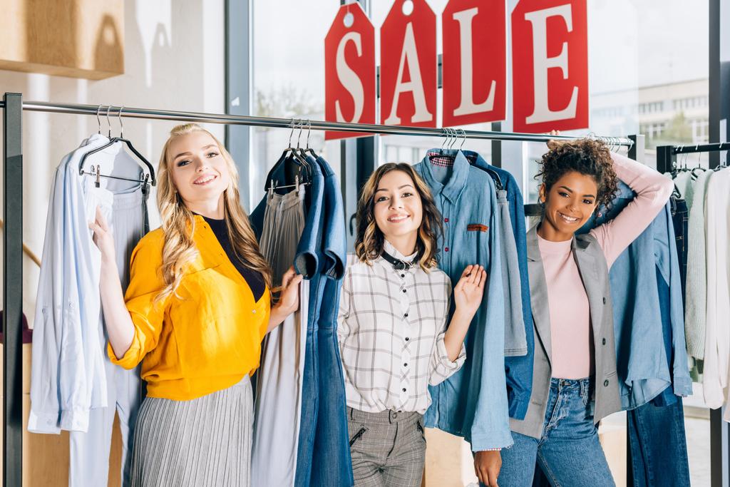 группа мультиэтнических молодых женщин на шопинге в магазине одежды
 - Фото, изображение