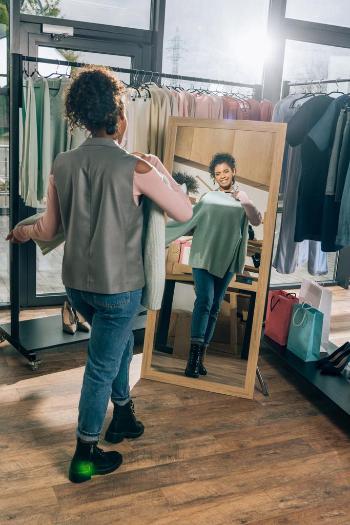 attrayant jeune femme regardant miroir dans magasin de vêtements
 - Photo, image
