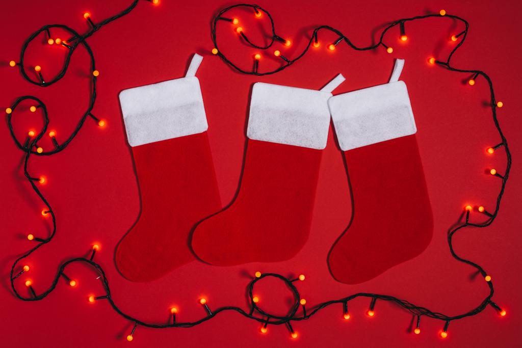 plat leggen met gearrangeerde lege kerst sokken en lichten isoleren don rood - Foto, afbeelding