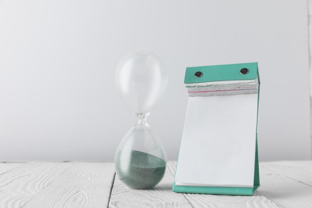vista de perto do calendário vazio e relógio de areia em mesa de madeira isolada em branco
 - Foto, Imagem