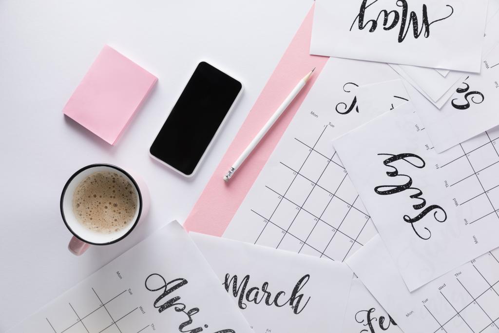 flache Liege mit Kalender, Smartphone, Tasse Kaffee und klebrigen Notizen isoliert auf weiß - Foto, Bild