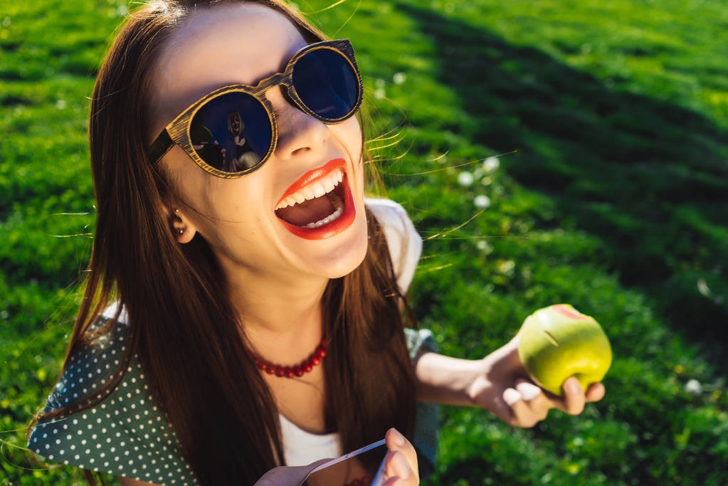 Happy smějící se ženu, otevřená ústa, sedí na zelené trávě v parku - Fotografie, Obrázek