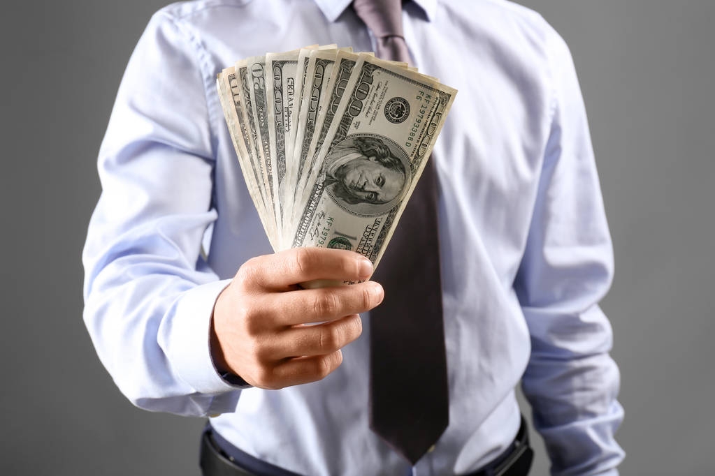 Człowiek w ubrania formalne trzyma pieniądze na szarym tle - Zdjęcie, obraz