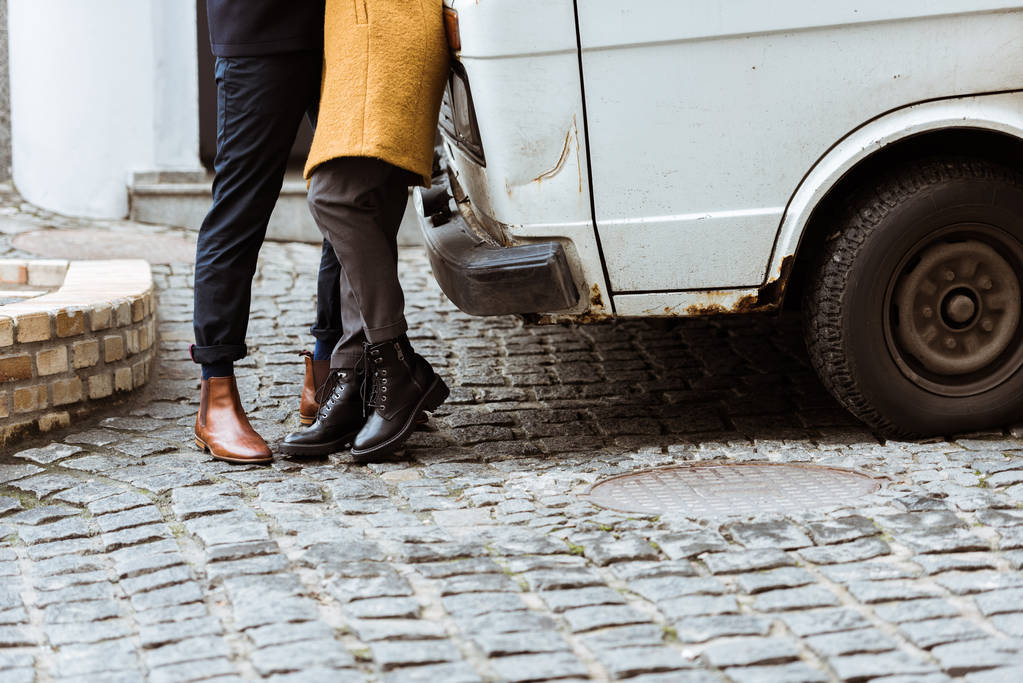abgeschnittenes Bild von Paar im Herbst-Outfit, das sich neben Auto umarmt - Foto, Bild