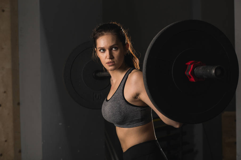 mujer muscular en un gimnasio haciendo ejercicios de peso pesado con barra de pesas
 - Foto, Imagen
