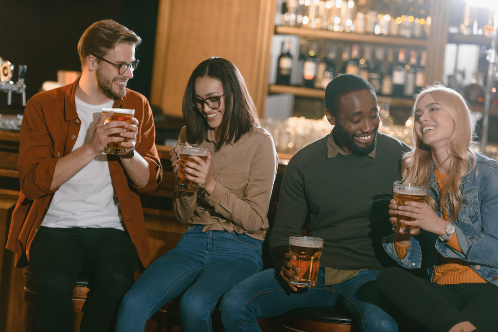 alegres amigos multiculturales bebiendo cerveza juntos en el bar
   - Foto, imagen