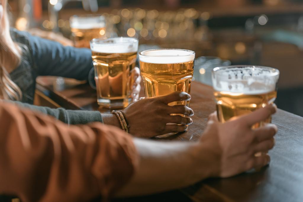cropped image of company holding glasses with beer at bar - Photo, Image