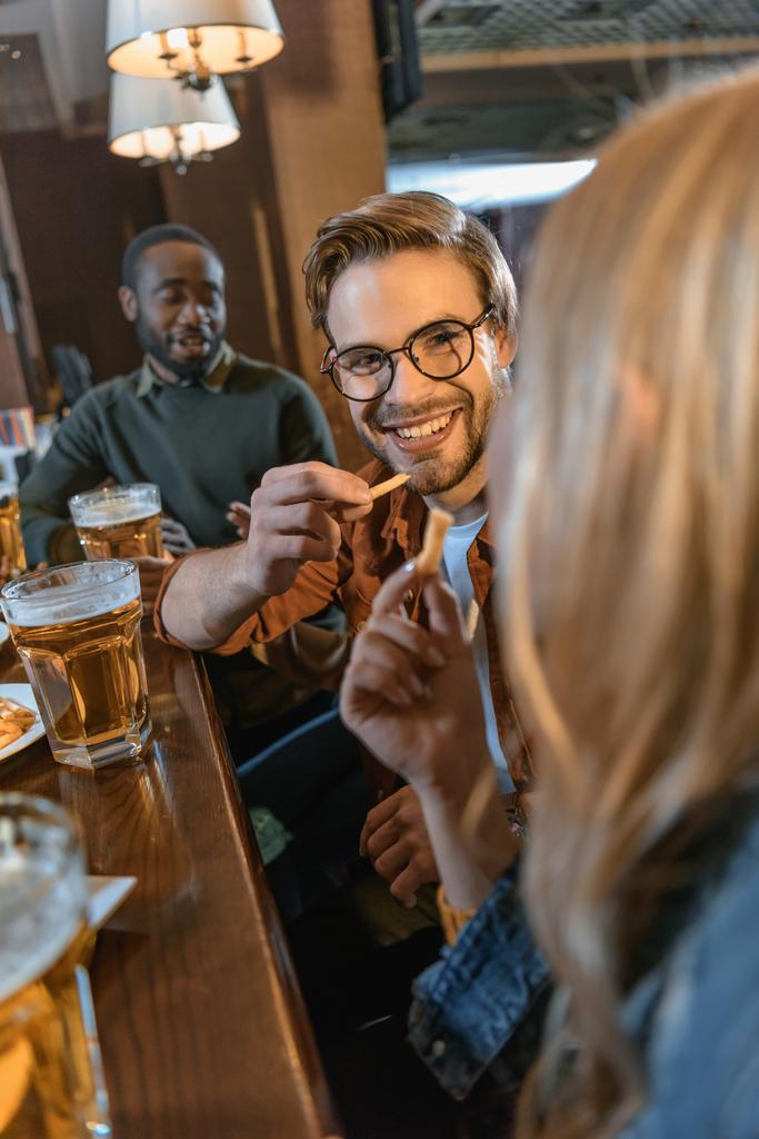 привлекательные мультикультурные друзья едят и пьют в баре
 - Фото, изображение