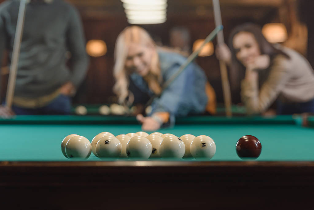 молодые многонациональные друзья играют в бильярд в баре
 - Фото, изображение