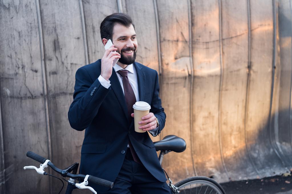 портрет веселого бизнесмена с кофе идти говорить по смартфону на улице
 - Фото, изображение