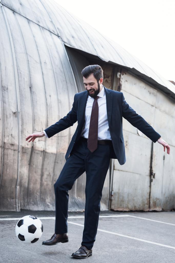 usmívající se podnikatel v obleku hrát fotbal na ulici - Fotografie, Obrázek