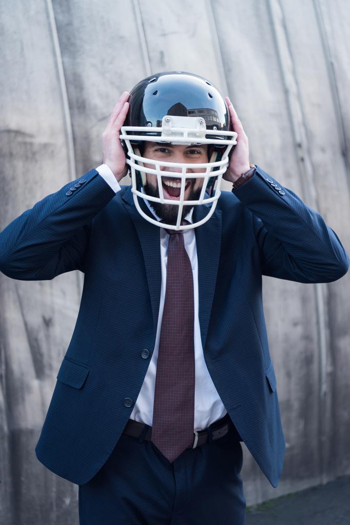 ritratto di uomo d'affari eccitato in giacca e cravatta e casco da rugby in strada
 - Foto, immagini
