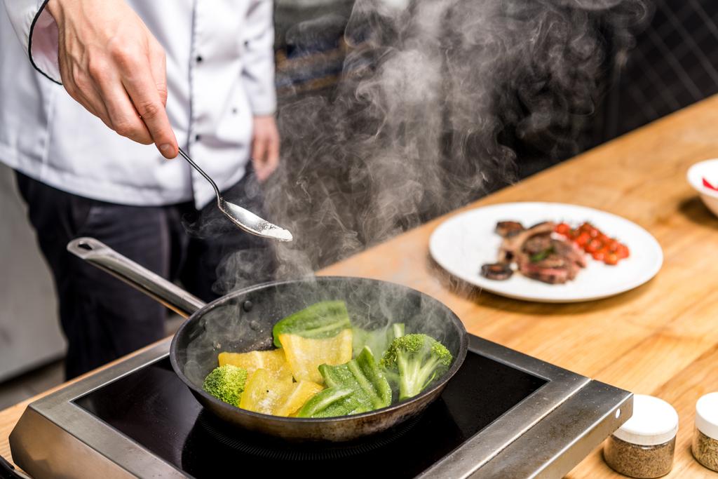 imagen recortada de chef freír pimientos amarillos y verdes con brócoli
 - Foto, imagen