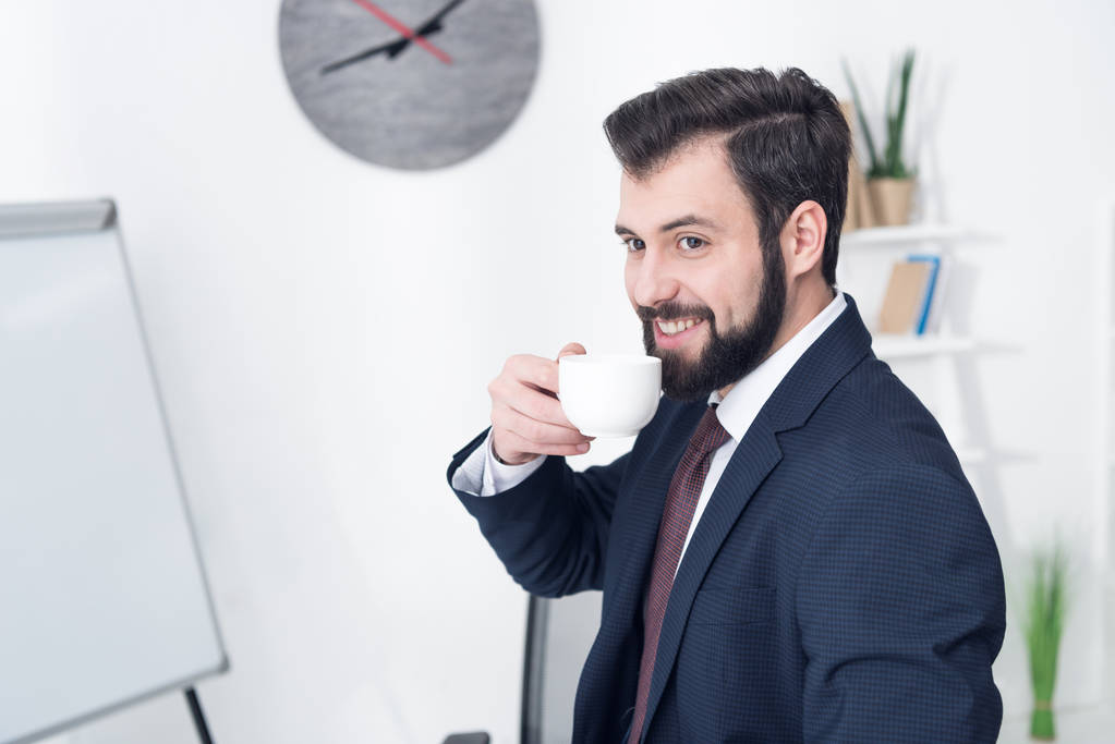 ritratto di un uomo d'affari sorridente che beve caffè in ufficio
 - Foto, immagini