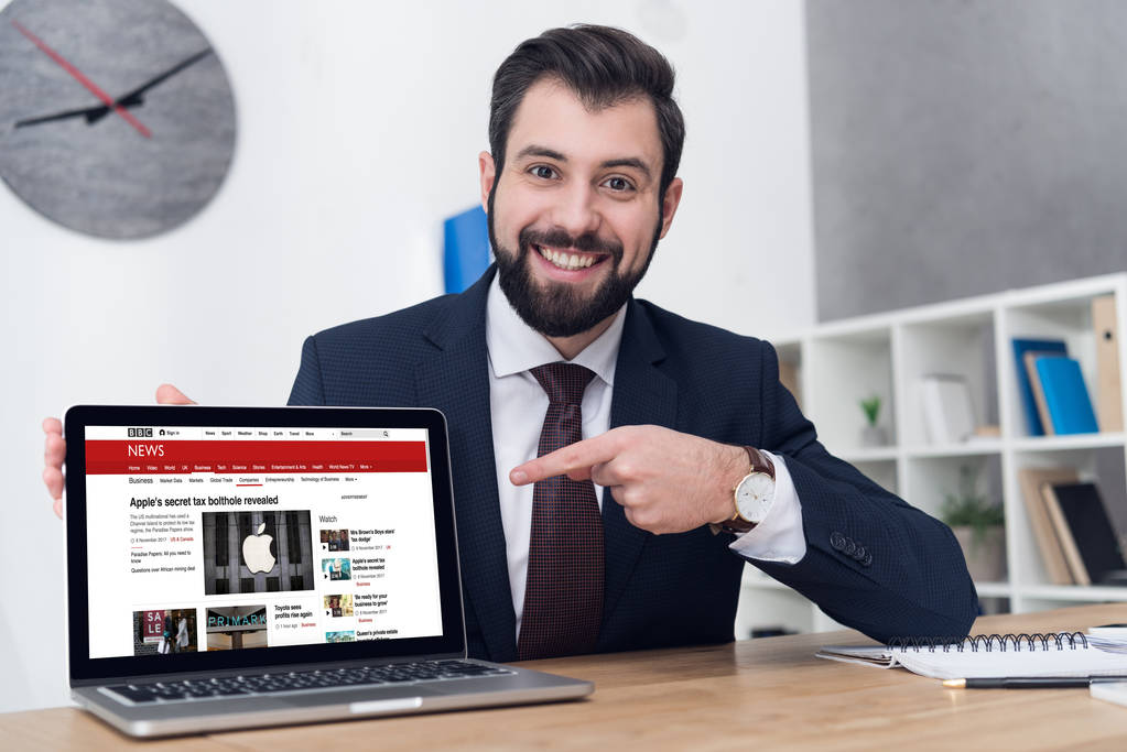 portrait d'un homme d'affaires souriant pointant vers un ordinateur portable sur le lieu de travail au bureau
 - Photo, image