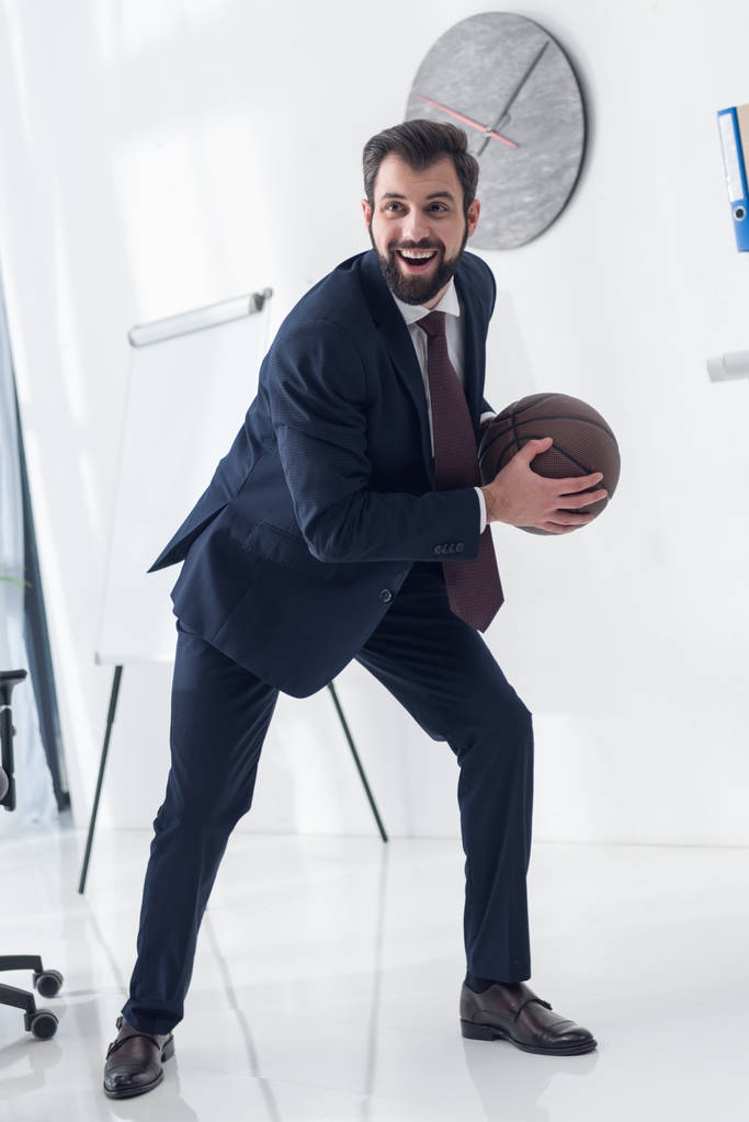 молодой бизнесмен в костюме играет в баскетбол в офисе
 - Фото, изображение