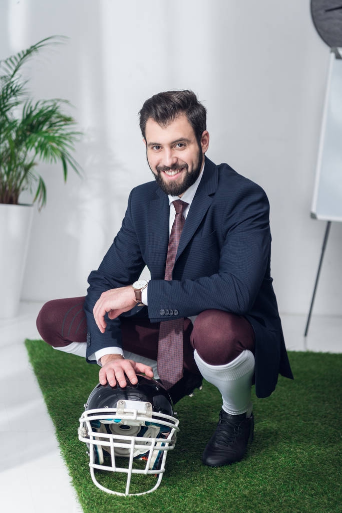 lachende zakenman met rugby helm in kantoor - Foto, afbeelding