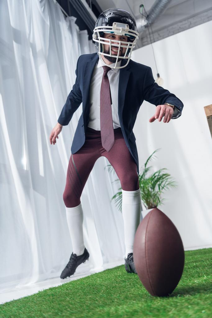бизнесмен в регби-шлеме играет в американский футбол в офисе
 - Фото, изображение