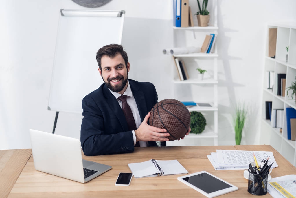 портрет молодого бизнесмена с баскетбольным мячом на рабочем месте в офисе
 - Фото, изображение