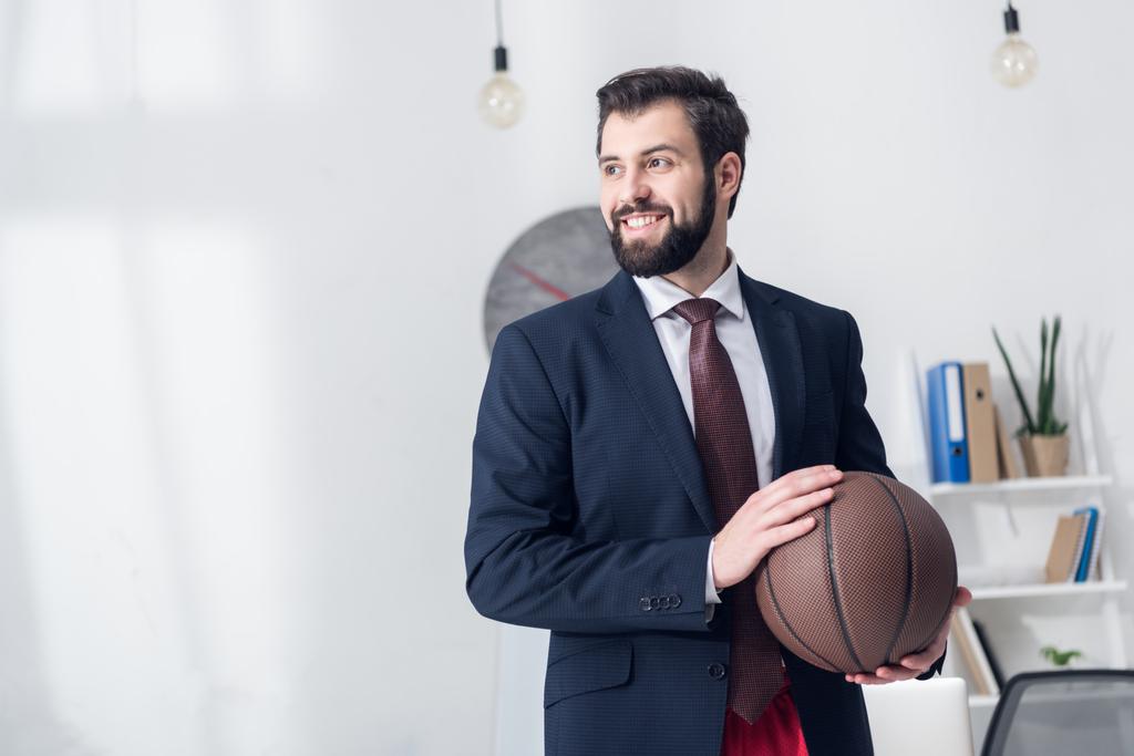 portrait of businessman in jacket holding basketball ball in office - Photo, Image