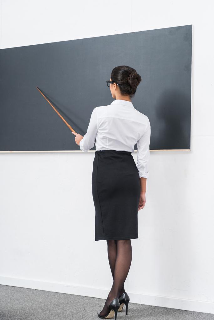 jonge aantrekkelijke leraar wijzend op leeg schoolbord - Foto, afbeelding