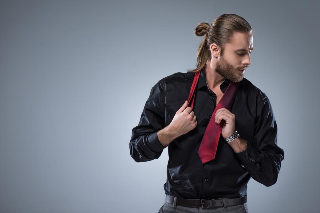Onun boynuna gri izole kırmızı kravat ile siyah tişörtlü adam genç sakallı   - Fotoğraf, Görsel