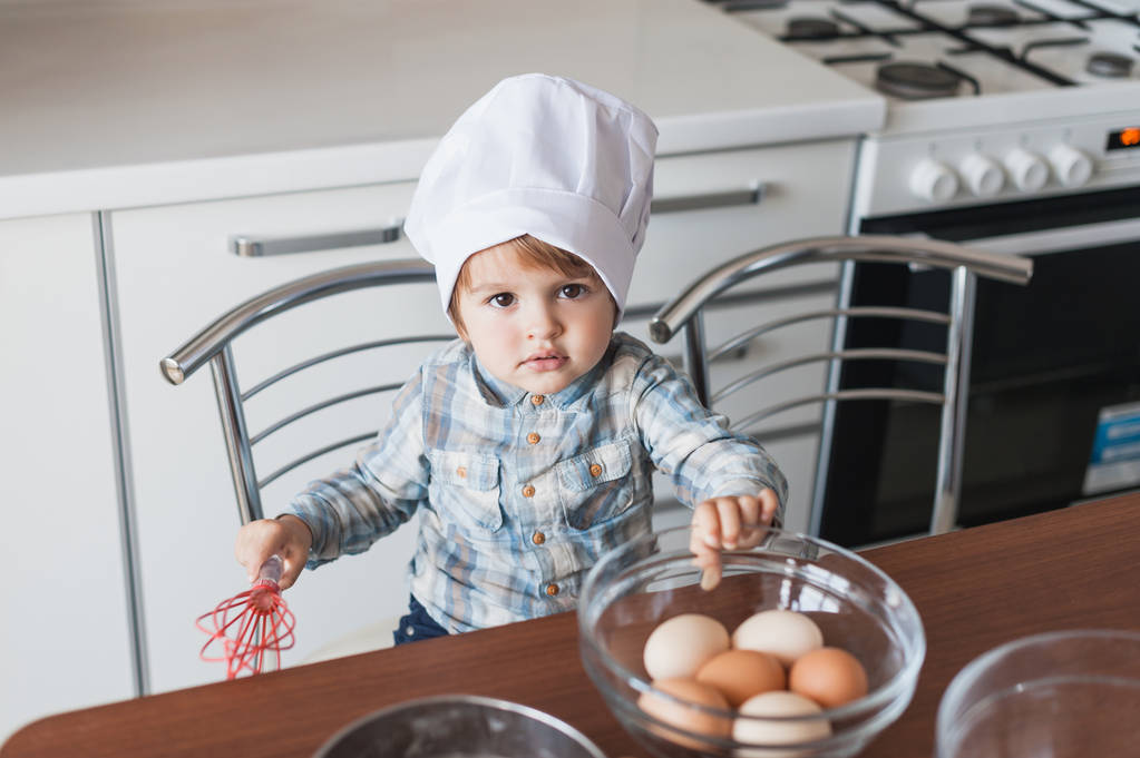 adorable little kid in chef hat with whisk and eggs in bowl - Photo, Image