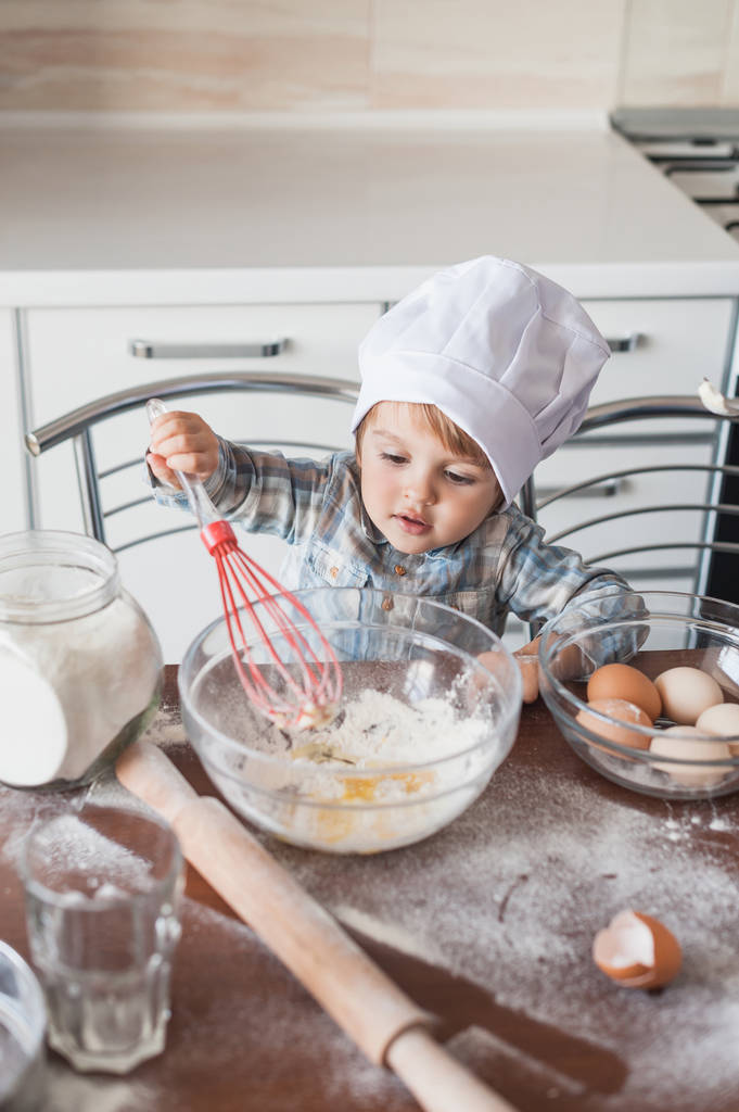 adorable petit enfant dans chapeau de chef préparer la pâte avec fouet à la cuisine
 - Photo, image